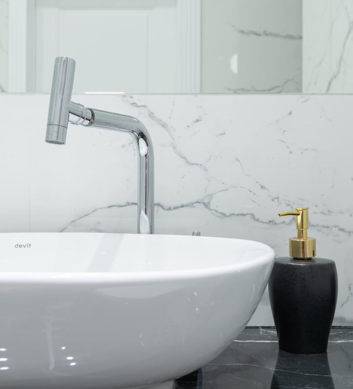 Elegant bathroom sink with chrome faucet and marble wall design.